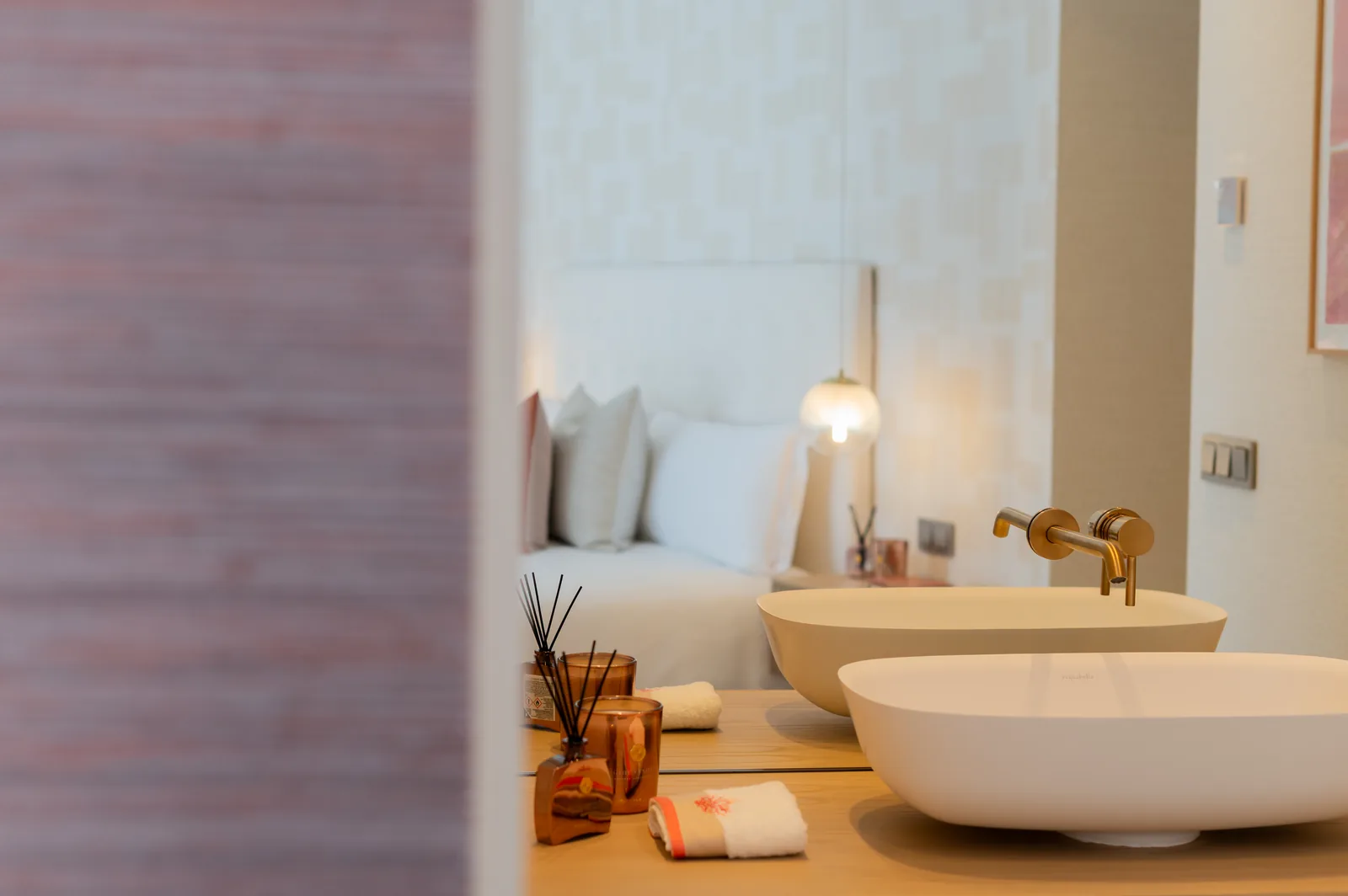 Doble lavabo sobre encimera de madera con vista al dormitorio a través del paso abierto