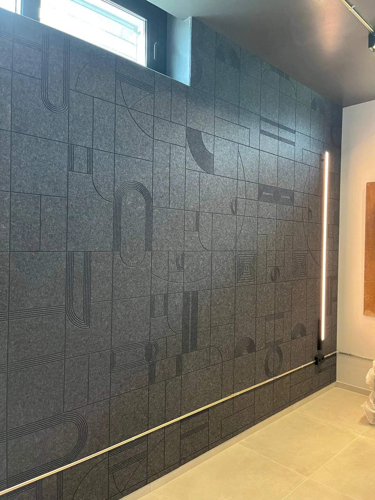Detalle del relieve geométrico grabado sobre los paneles acústicos de fieltro gris