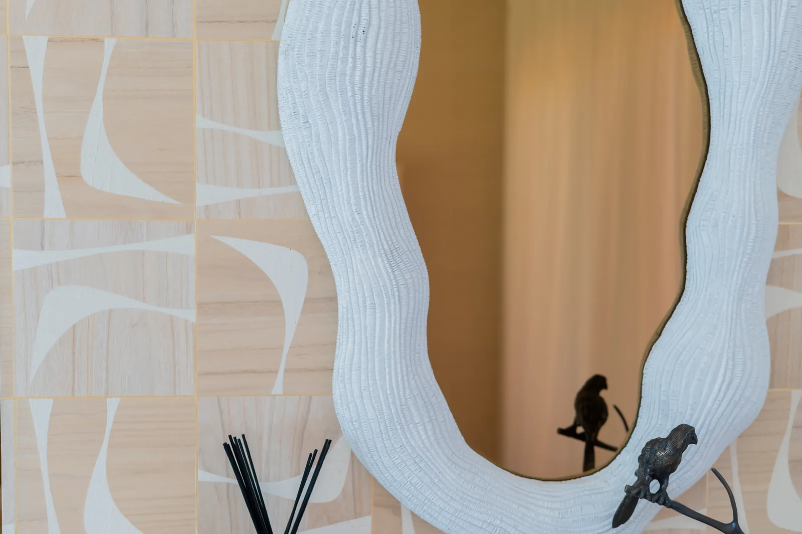 Espejo de forma orgánica en blanco texturizado sobre pared de marquetería de madera